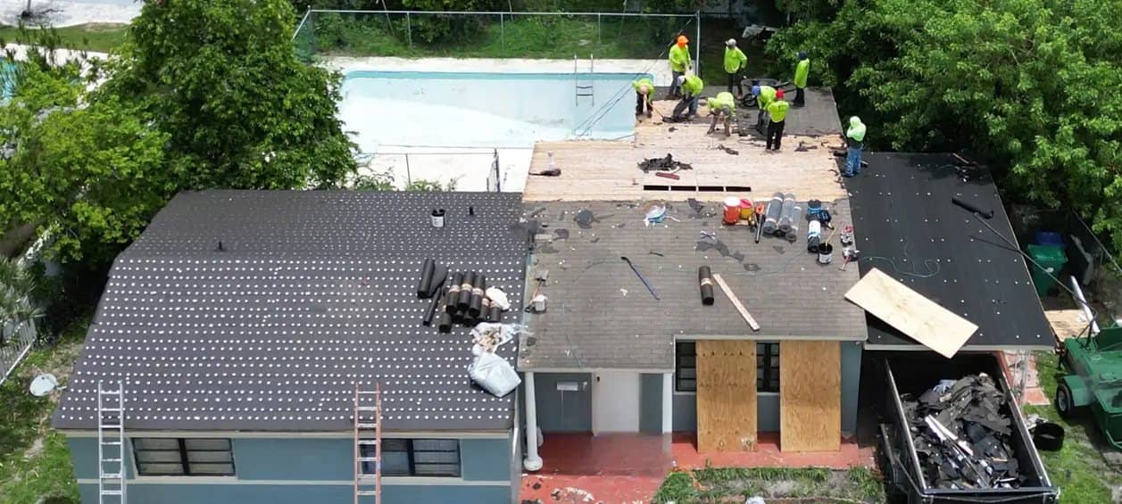 Crew repairing a shingle roof, seen from above