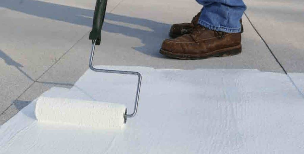 White silicone coating being rolled onto a flat roof