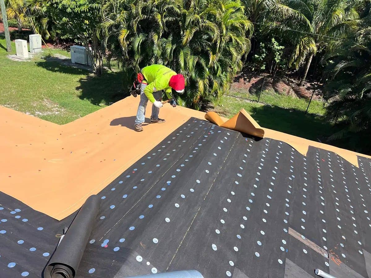 Roofer installing self-adhered underlayment during a roof repair