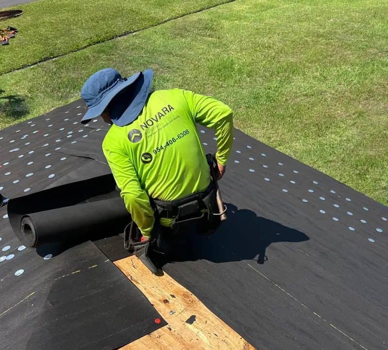 Roofing crew member rolling out underlayment on a residential roof deck