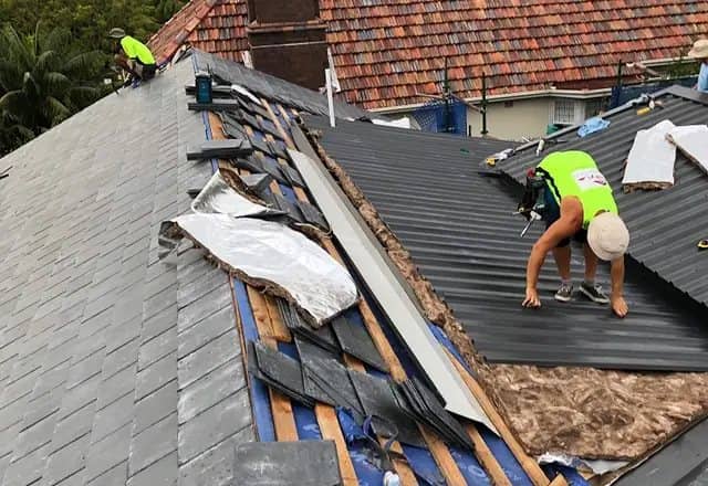 Roofer tearing off old shingles during a roof repair